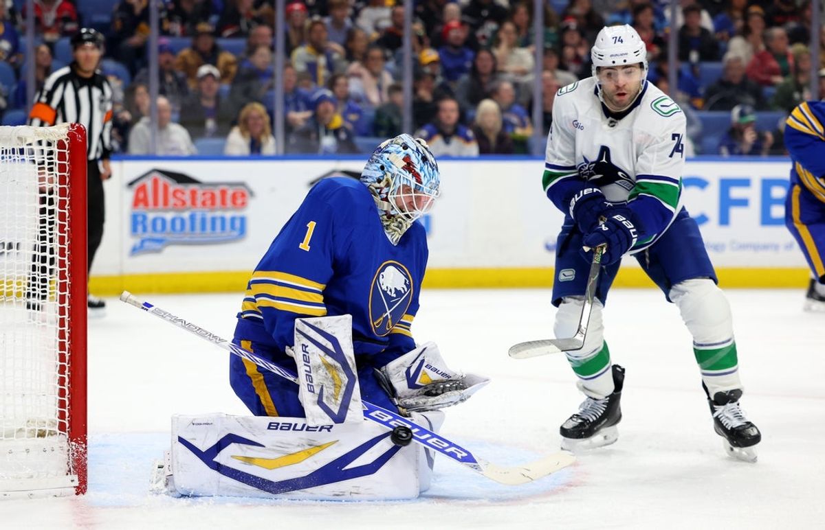 Jan 6, 2026; Buffalo, New York, USA;  Vancouver Canucks left wing Jake Debrusk (74) tries to deflect a shot on Buffalo Sabres goaltender Ukko-Pekka Luukkonen (1) during the first period at KeyBank Center. Mandatory Credit: Timothy T. Ludwig-Imagn Images