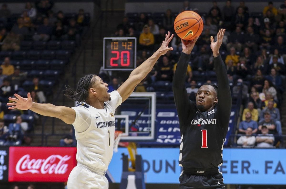 Jan 6, 2026; Morgantown, West Virginia, USA; Cincinnati Bearcats guard Day Day Thomas (1) shoots a three pointer over West Virginia Mountaineers guard Jasper Floyd (1) during the first half at Hope Coliseum. Mandatory Credit: Ben Queen-Imagn Images