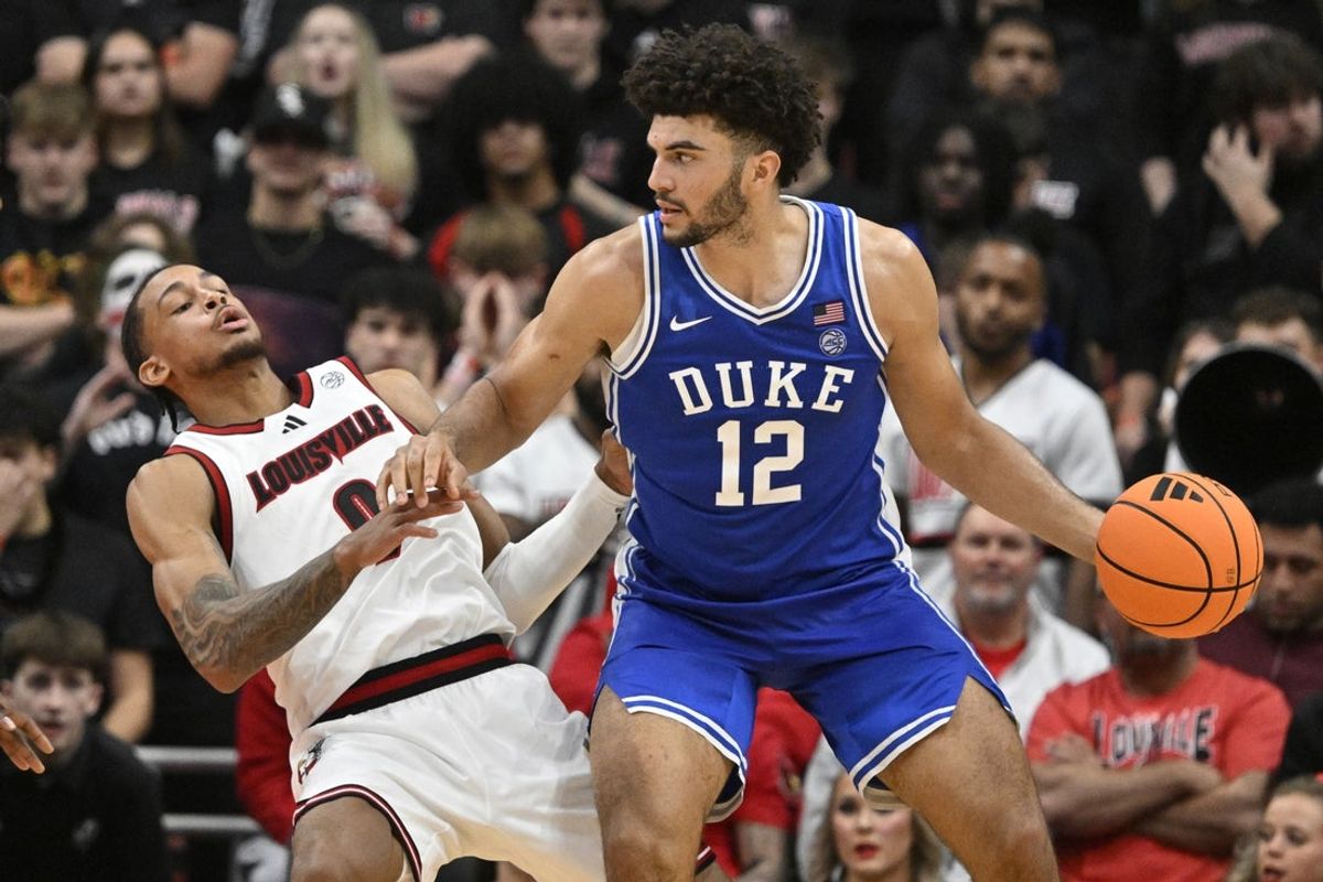 Jan 6, 2026; Louisville, Kentucky, USA;  Duke Blue Devils forward Cameron Boozer (12) charges into Louisville Cardinals forward Khani Rooths (9) during the second half at KFC Yum! Center. Mandatory Credit: Jamie Rhodes-Imagn Images