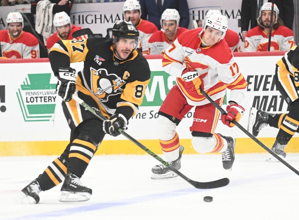 Jan 10, 2026; Pittsburgh, Pennsylvania, USA;  Pittsburgh Penguins center Sidney Crosby (87) moves the puck as Calgary Flames center Yegor Sharangovich (17) during the first period at PPG Paints Arena. Mandatory Credit: Philip G. Pavely-Imagn Images