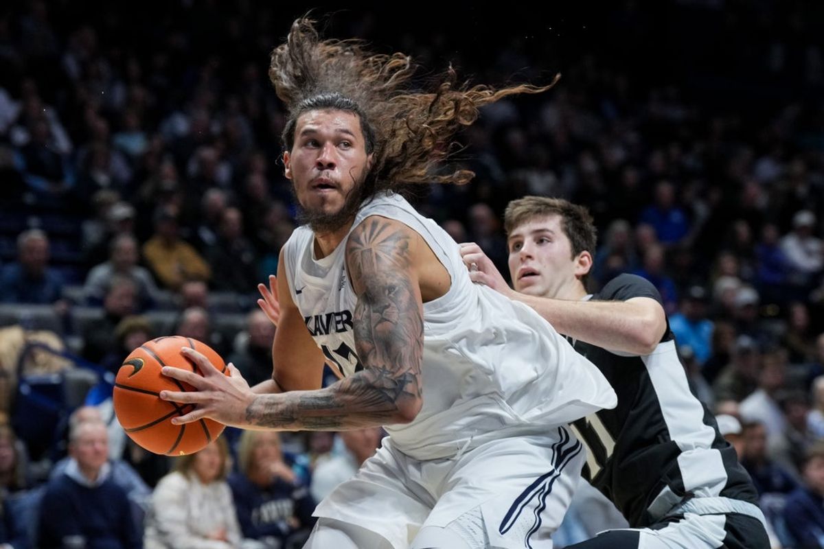 Jan 10, 2026; Cincinnati, Ohio, USA; Xavier Musketeers forward Tre Carroll (12) drives to the basket against Providence Friars guard Ryan Mela (11) in the first half at the Cintas Center. Mandatory Credit: Aaron Doster-Imagn Images