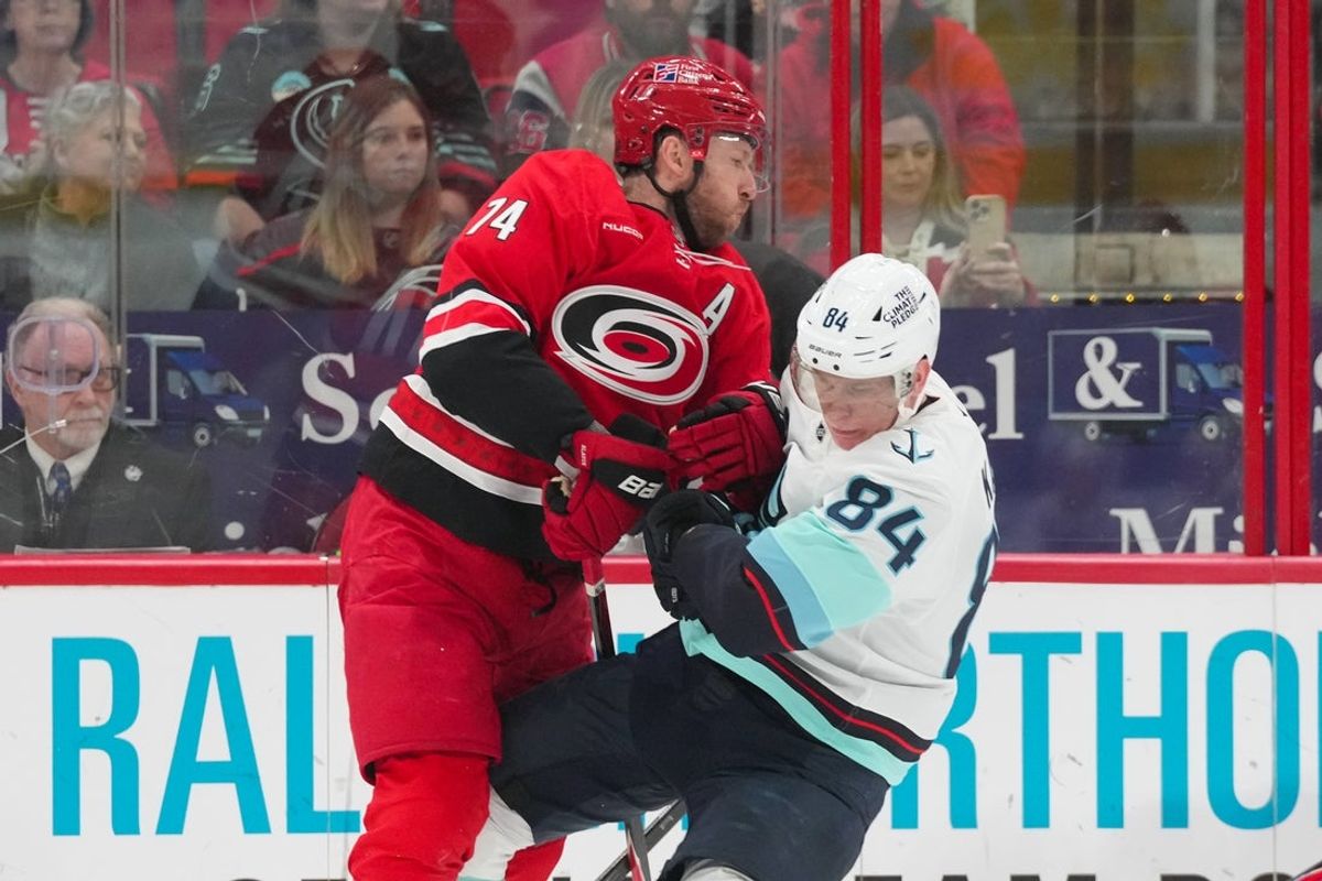 Jan 10, 2026; Raleigh, North Carolina, USA;  Carolina Hurricanes defenseman Jaccob Slavin (74) checks Seattle Kraken right wing Kaapo Kakko (84) during the first period at Lenovo Center. Mandatory Credit: James Guillory-Imagn Images