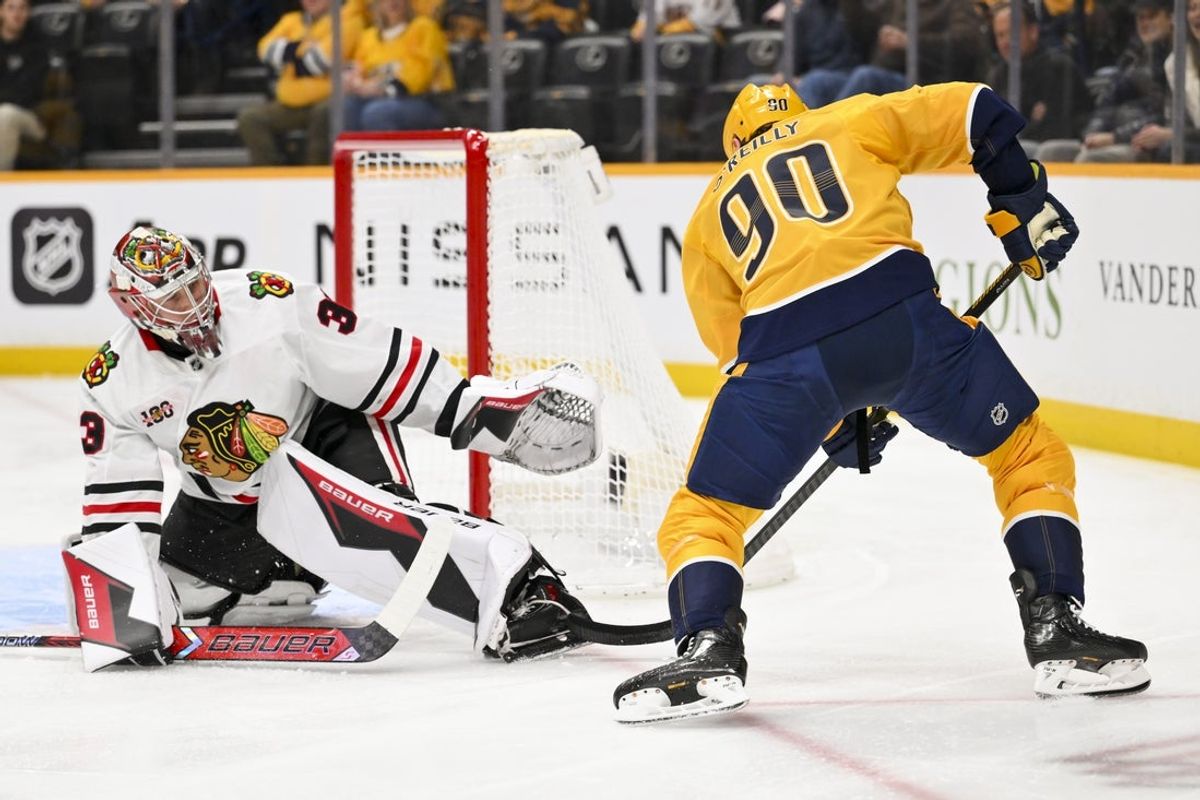 Jan 10, 2026; Nashville, Tennessee, USA;  Chicago Blackhawks goaltender Drew Commesso (33) blocks the shot of Nashville Predators center Ryan O'Reilly (90) during the first period at Bridgestone Arena. Mandatory Credit: Steve Roberts-Imagn Images