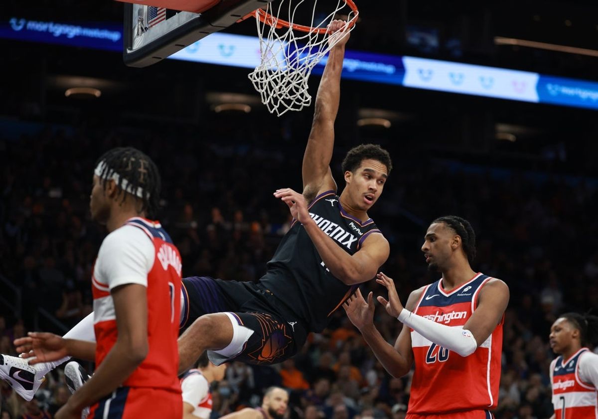 Jan 11, 2026; Phoenix, Arizona, USA; Phoenix Suns forward Oso Ighodaro (11) hangs from the rim after a dunk against the Washington Wizards in the first half at Mortgage Matchup Center. Mandatory Credit: Mark J. Rebilas-Imagn Images