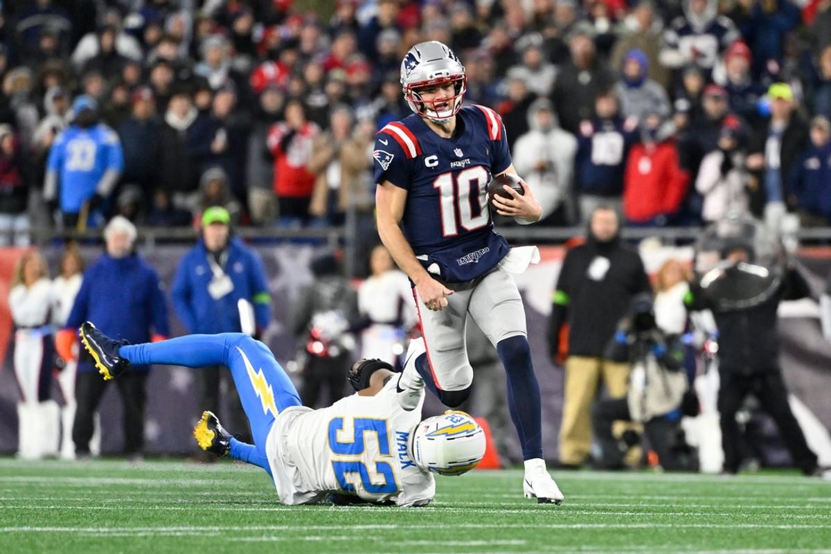 Jan 11, 2026; Foxborough, MA, USA; New England Patriots quarterback Drake Maye (10) breaks a tackle by Los Angeles Chargers linebacker Khalil Mack (52) and runs the ball during the first half in an AFC Wild Card Round game at Gillette Stadium. Mandatory Credit: Eric Canha-Imagn Images