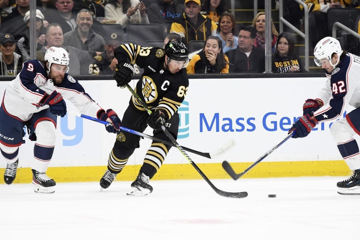 Dec 3, 2023; Boston, Massachusetts, USA; Boston Bruins left wing Brad Marchand (63) tries to control the puck between Columbus Blue Jackets defenseman Ivan Provorov (9) and center Alexandre Texier (42) during the first period at TD Garden.