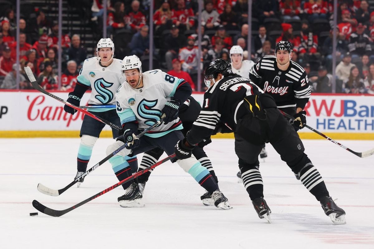 Jan 14, 2026; Newark, New Jersey, USA; Seattle Kraken center Frederick Gaudreau (89) plays the puck as New Jersey Devils defenseman Jonas Siegenthaler (71) defends during the first period at Prudential Center. Mandatory Credit: Ed Mulholland-Imagn Images