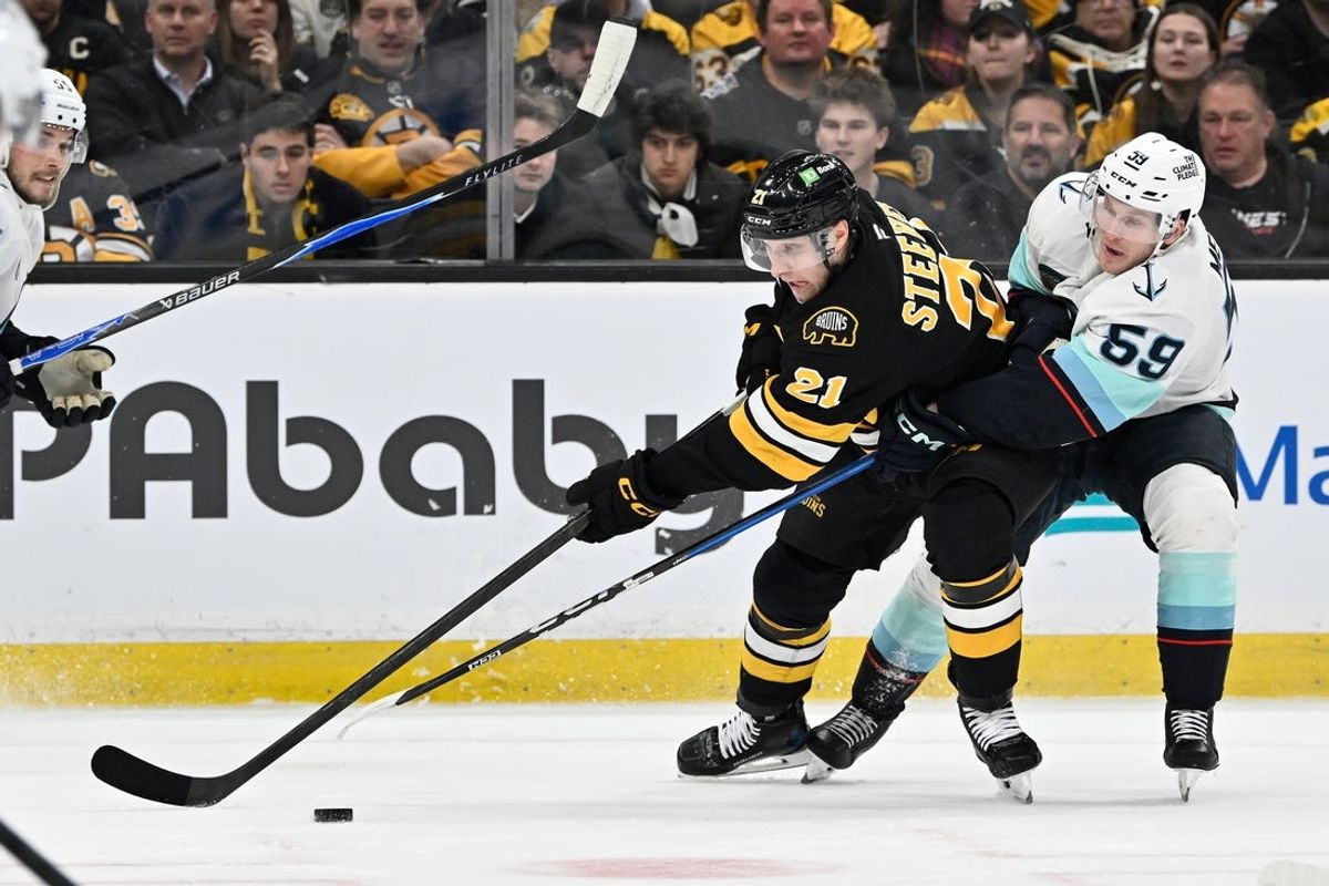 Jan 15, 2026; Boston, Massachusetts, USA; Boston Bruins center Alex Steeves (21) passes the puck defended by Seattle Kraken center Ben Meyers (59) during the first period at TD Garden. Mandatory Credit: Eric Canha-Imagn Images