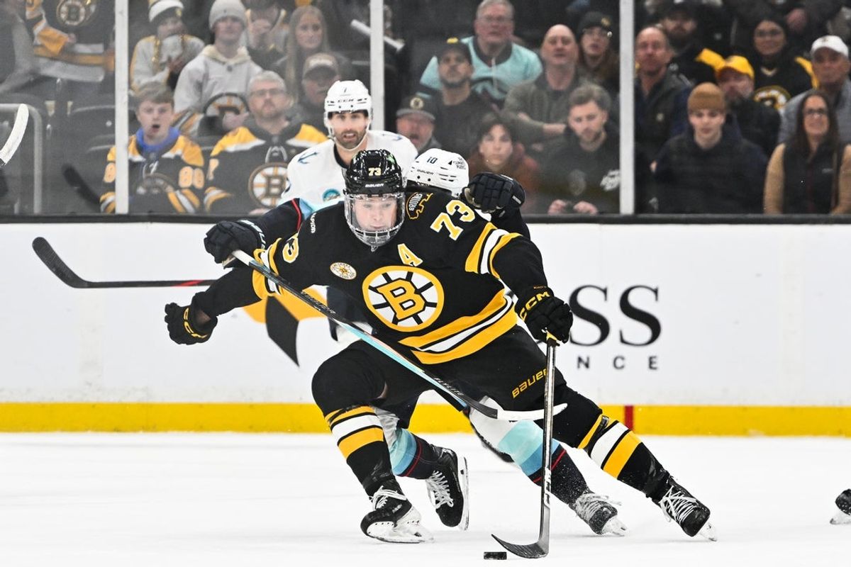 Jan 15, 2026; Boston, Massachusetts, USA; Boston Bruins defenseman Charlie McAvoy (73) controls the puck with Seattle Kraken center Matty Beniers (10) trying to check from behind during the third period at TD Garden. Mandatory Credit: Eric Canha-Imagn Images