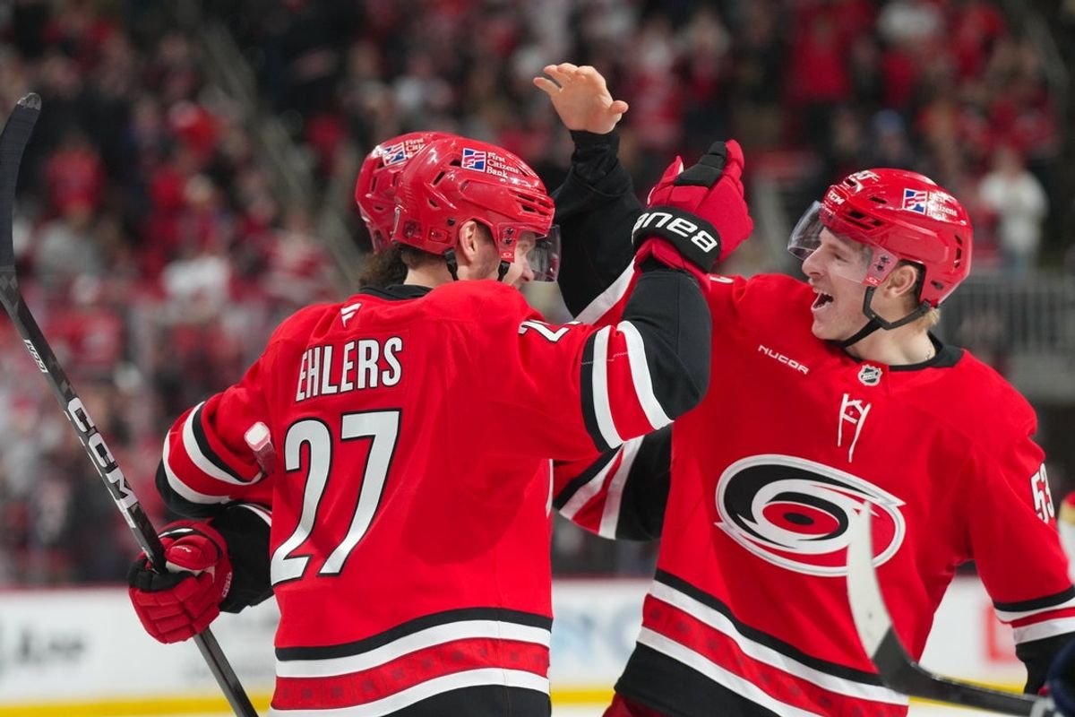 Jan 16, 2026; Raleigh, North Carolina, USA;  Carolina Hurricanes left wing Nikolaj Ehlers (27) is congratulated after his hat trick goal by defenseman Jalen Chatfield (5) and right wing Jackson Blake (53) against the Florida Panthers during the third period at Lenovo Center. Mandatory Credit: James Guillory-Imagn Images
