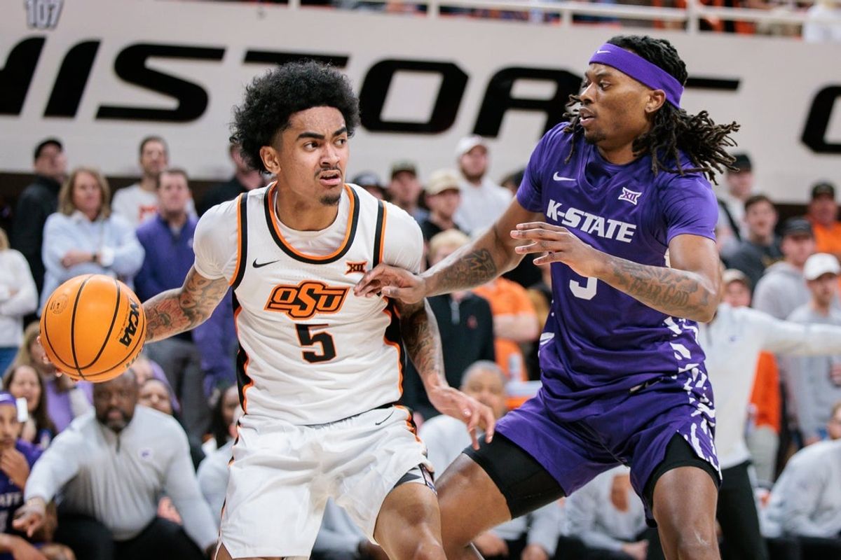 Jan 17, 2026; Stillwater, Oklahoma, USA; Vyctorius Miller (5) of the Oklahoma State Cowboys drives to the basket around C.J. Jones (3) of the Kansas State Wildcats during the first half at Gallagher-Iba Arena. Mandatory Credit: William Purnell-Imagn Images