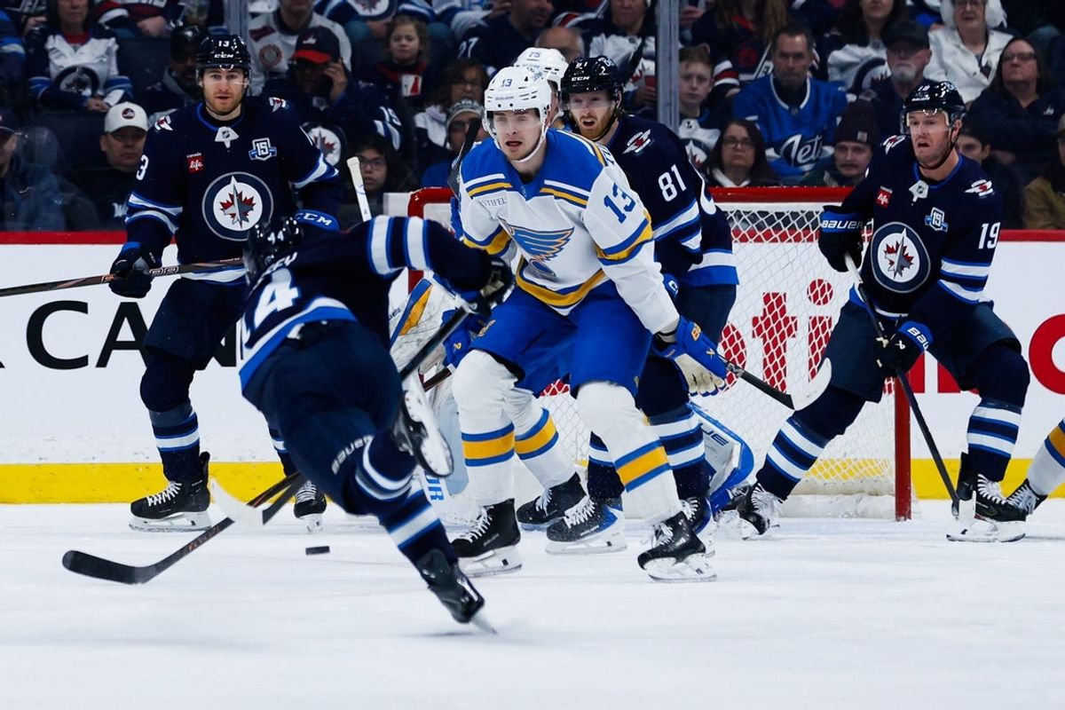 Jan 20, 2026; Winnipeg, Manitoba, CAN;  St. Louis Blues forward Alexey Toropchenko (13) and Winnipeg Jets forward Kyle Connor (81) watch a shot by defenseman Josh Morrissey (44) during the first period at Canada Life Centre. Mandatory Credit: Terrence Lee-Imagn Images