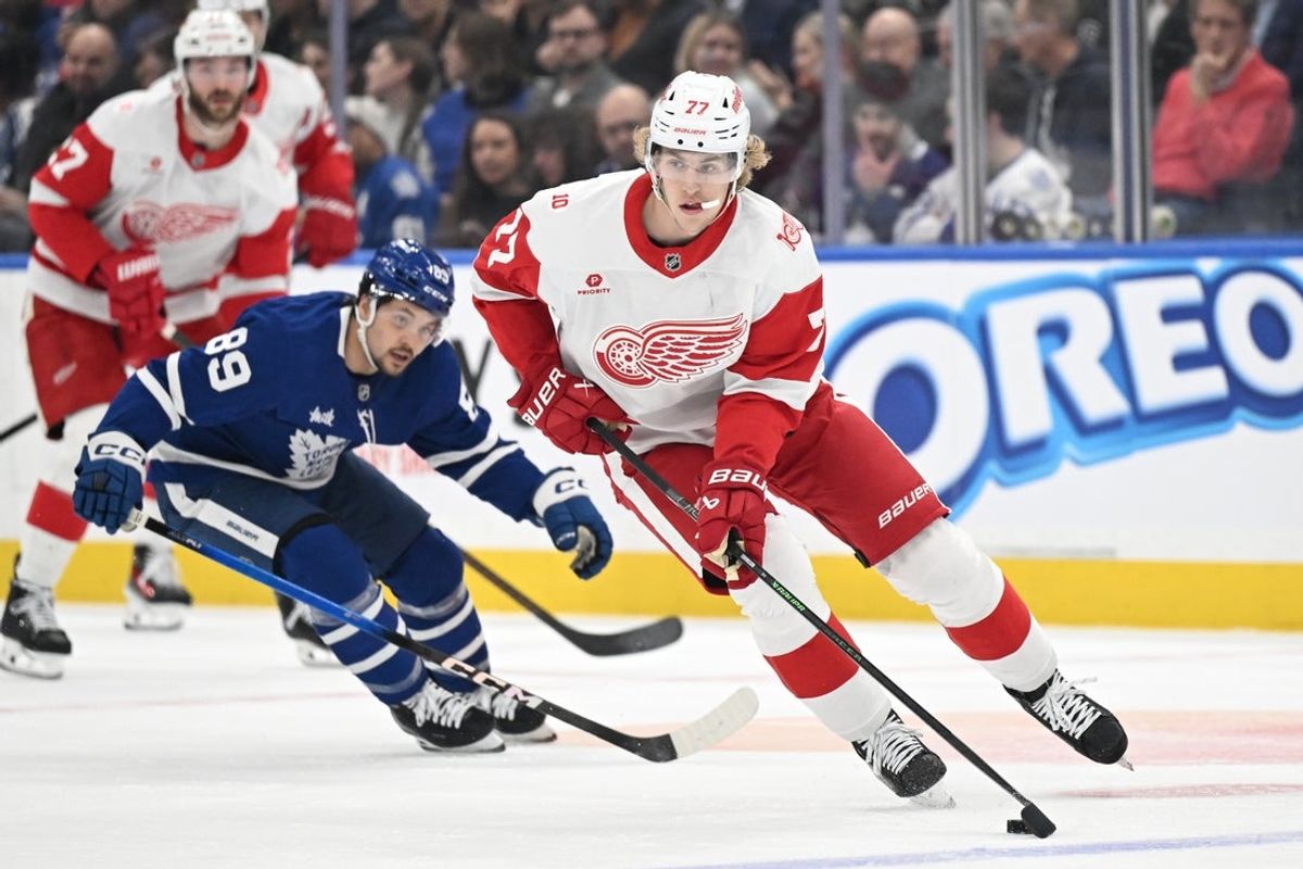 Jan 21, 2026; Toronto, Ontario, CAN;  Detroit Red Wings defenseman Simon Edvinsson (77) skates the puck away from Toronto Maple Leafs forward Nick Robertson (89) in the first period at Scotiabank Arena. Mandatory Credit: Dan Hamilton-Imagn Images
