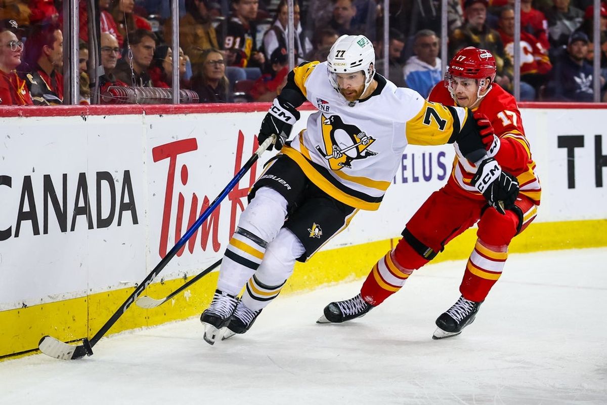 Jan 21, 2026; Calgary, Alberta, CAN; Pittsburgh Penguins defenseman Brett Kulak (77) controls the puck against Calgary Flames center Yegor Sharangovich (17) during the second period at Scotiabank Saddledome. Mandatory Credit: Sergei Belski-Imagn Images