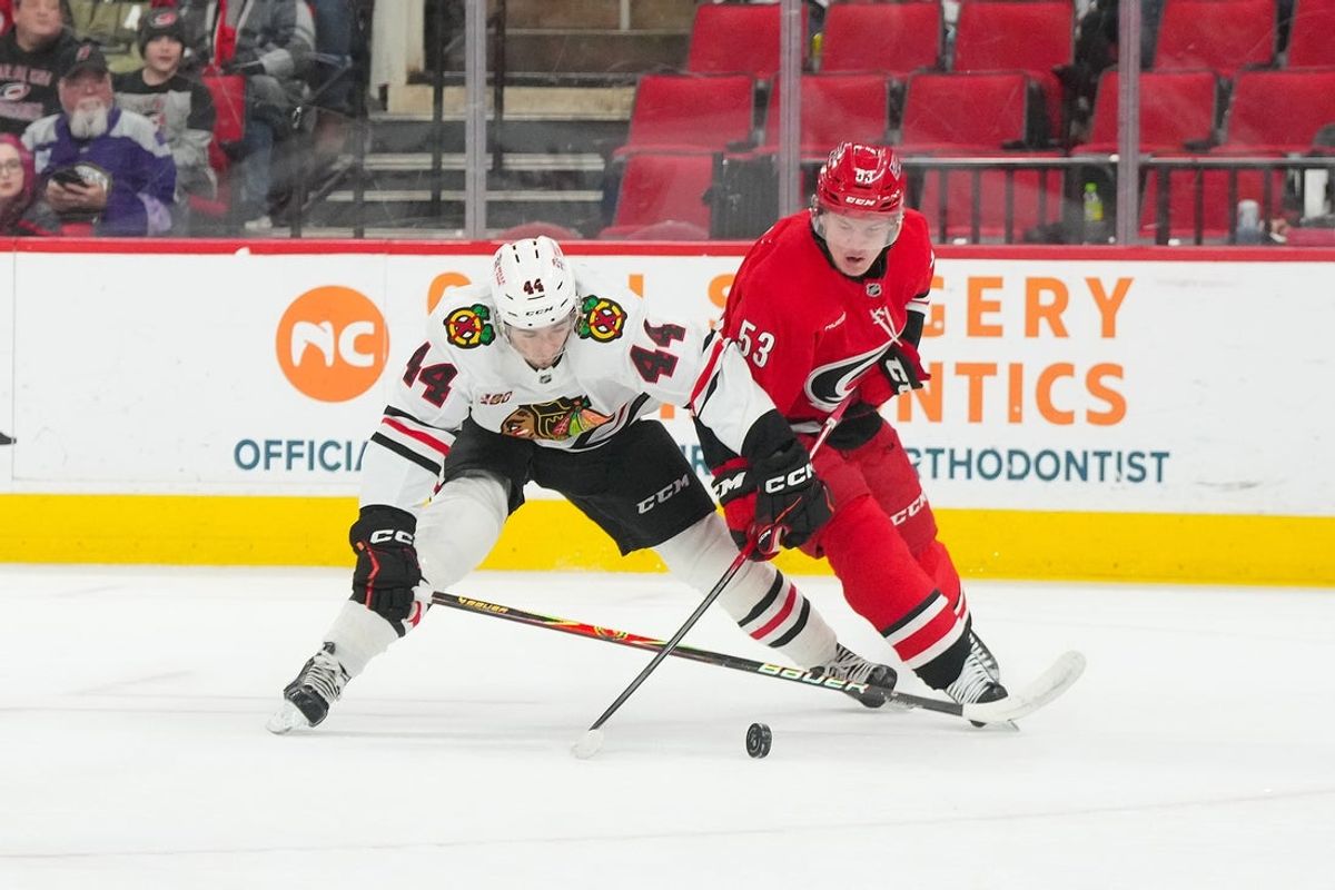 Jan 22, 2026; Raleigh, North Carolina, USA;  Carolina Hurricanes right wing Jackson Blake (53) and Chicago Blackhawks defenseman Wyatt Kaiser (44) battle over the puck during the first period at Lenovo Center. Mandatory Credit: James Guillory-Imagn Images