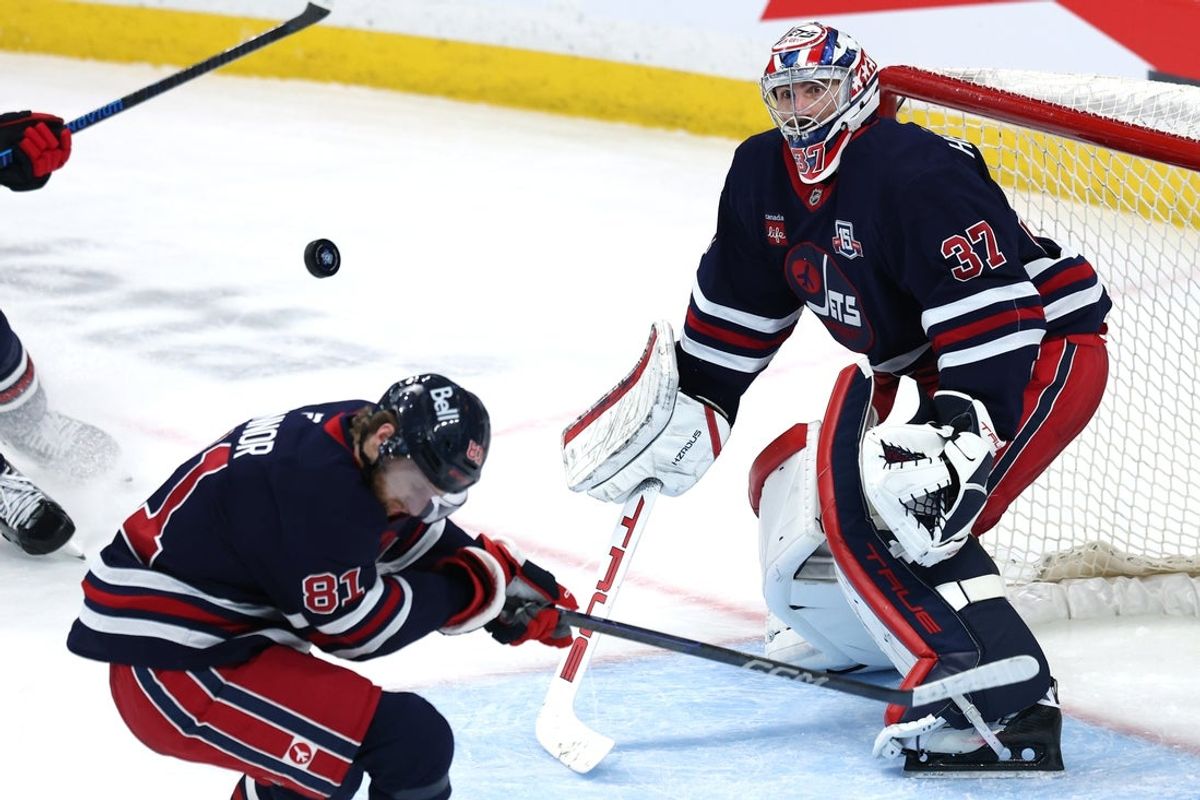 Jan 22, 2026; Winnipeg, Manitoba, CAN; Winnipeg Jets left wing Kyle Connor (81) ducks from a shot on Winnipeg Jets goaltender Connor Hellebuyck (37) during a game against the Florida Panthers in the third period at Canada Life Centre. Mandatory Credit: James Carey Lauder-Imagn Images