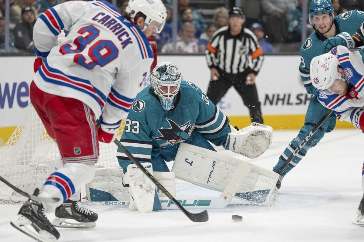 Jan 23, 2026; San Jose, California, USA;  San Jose Sharks goaltender Alex Nedeljkovic (33) watches the puck during the first period against New York Rangers center Sam Carrick (39) at SAP Center at San Jose. Mandatory Credit: Stan Szeto-Imagn Images
