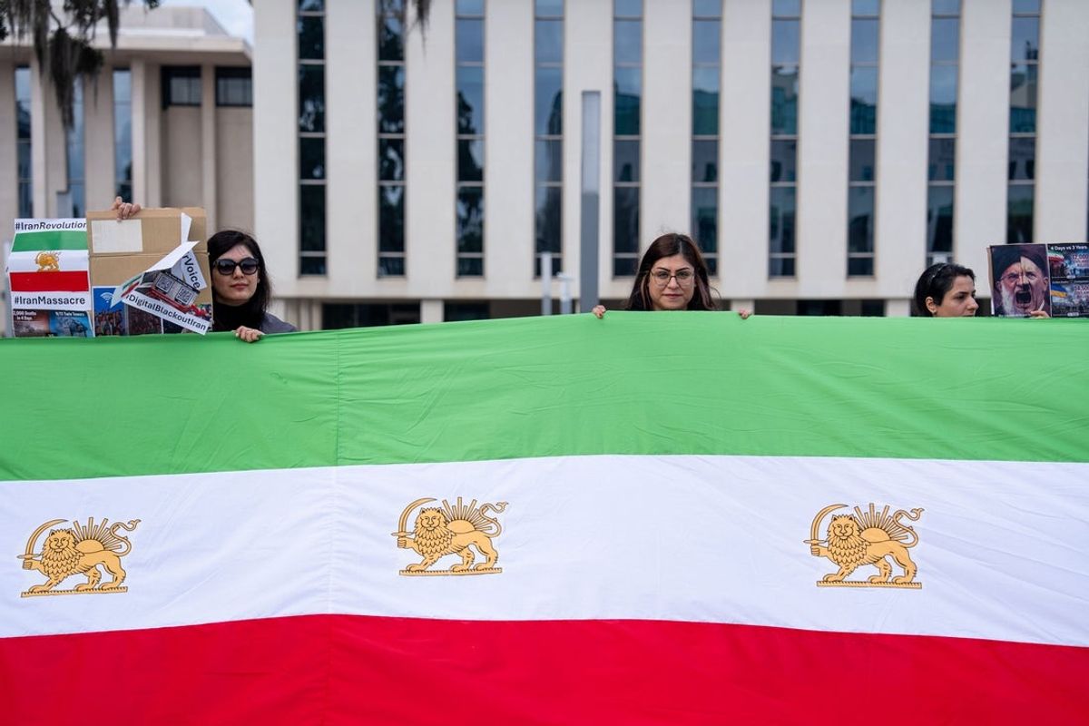 A small crowd of people gathered in front of the Florida House of Representatives hold signs and flags as they advocate to free Iran, Saturday, Jan. 24, 2026.