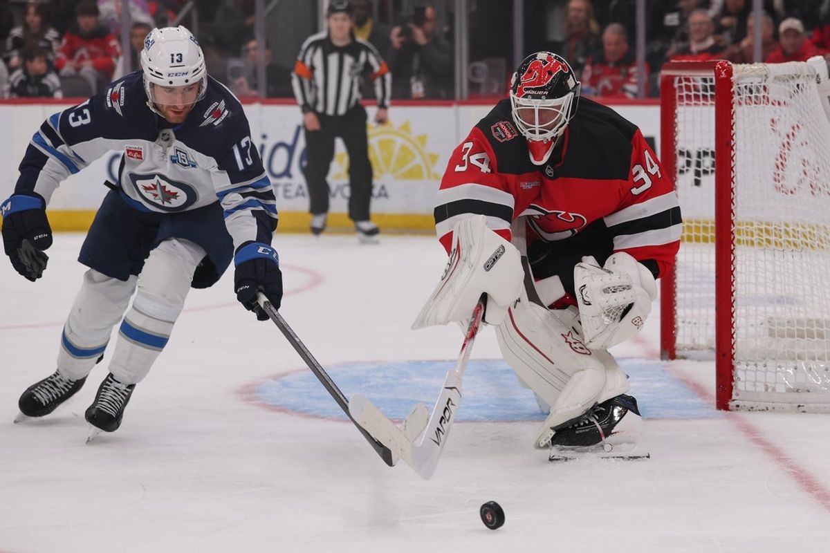 Jan 27, 2026; Newark, New Jersey, USA; New Jersey Devils goaltender Jake Allen (34) plays the puck away from Winnipeg Jets center Gabriel Vilardi (13) during the third period at Prudential Center. Mandatory Credit: Ed Mulholland-Imagn Images