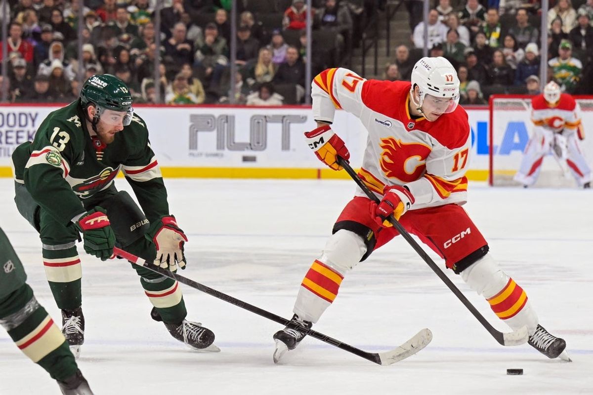 Jan 29, 2026; Saint Paul, Minnesota, USA;  Calgary Flames forward Yegor Sharangovich (17) controls the puck as Minnesota Wild forward Yakov Trenin (13) back checks during the first period at Grand Casino Arena. Mandatory Credit: Nick Wosika-Imagn Images