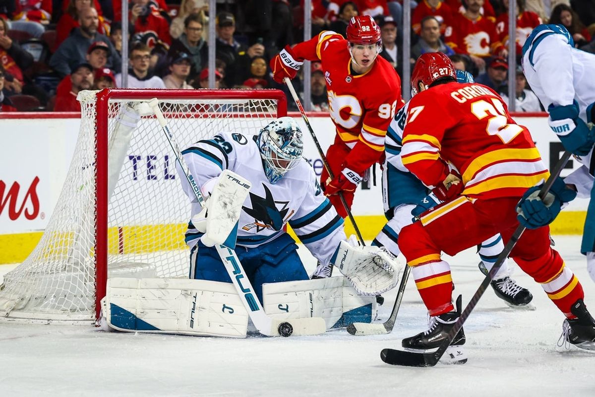Jan 31, 2026; Calgary, Alberta, CAN; San Jose Sharks goaltender Alex Nedeljkovic (33) makes a save against Calgary Flames right wing Matt Coronato (27) during the second period at Scotiabank Saddledome. Mandatory Credit: Sergei Belski-Imagn Images