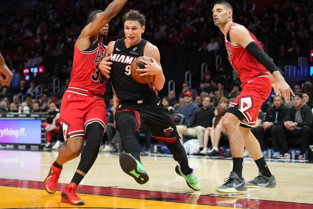 Feb 1, 2026; Miami, Florida, USA;  Miami Heat guard Pelle Larsson (9) splits the defense of Chicago Bulls forward Isaac Okoro (35) and center Nikola Vucevic (9) during the second half at Kaseya Center. Mandatory Credit: Jim Rassol-Imagn Images