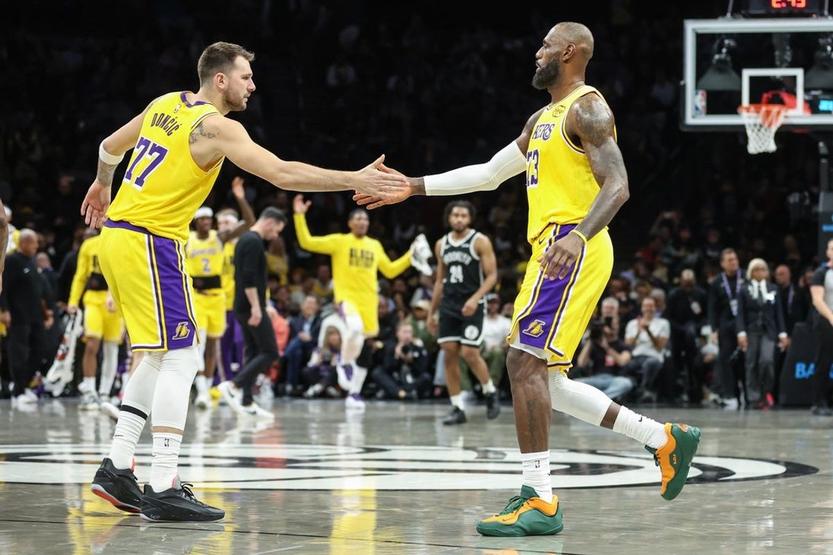 Feb 3, 2026; Brooklyn, New York, USA;  Los Angeles Lakers guard Luka Doncic (77) greets forward LeBron James (23) during a timeout in the first quarter against the Brooklyn Nets at Barclays Center. Mandatory Credit: Wendell Cruz-Imagn Images