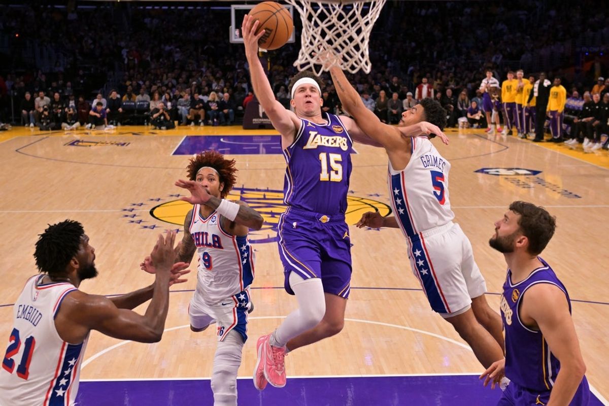 Feb 5, 2026; Los Angeles, California, USA;  Los Angeles Lakers guard Austin Reaves (15) drives past Philadelphia 76ers guard Kelly Oubre Jr. (9) and guard Quentin Grimes (5) in the second half at Crypto.com Arena. Mandatory Credit: Jayne Kamin-Oncea-Imagn Images