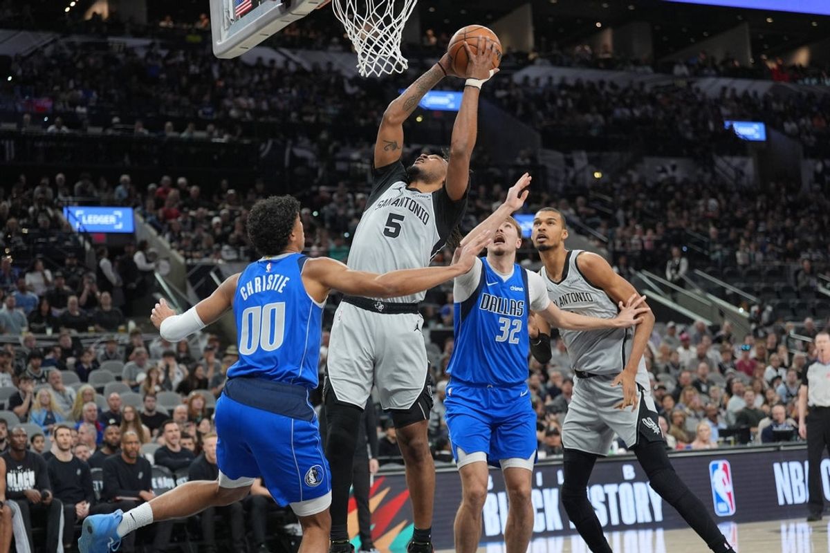 Feb 7, 2026; San Antonio, Texas, USA;  San Antonio Spurs guard Stephon Castle (5) goes up for a shot between Dallas Mavericks guard Max Christie (00) and forward Cooper Flagg (32) in the first half at Frost Bank Center. Mandatory Credit: Daniel Dunn-Imagn Images