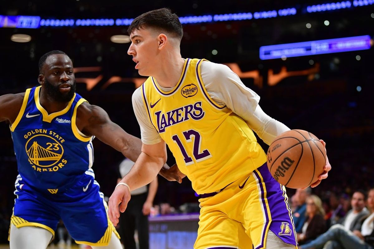 Feb 7, 2026; Los Angeles, California, USA; Los Angeles Lakers forward Jake LaRavia (12) moves to the basket against Golden State Warriors forward Draymond Green (23) during the first half at Crypto.com Arena. Mandatory Credit: Gary A. Vasquez-Imagn Images