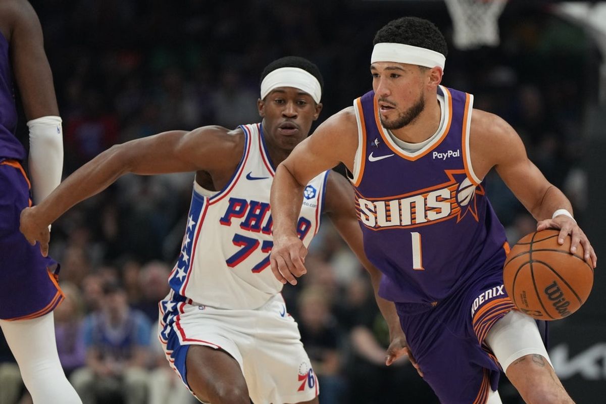 Feb 7, 2026; Phoenix, Arizona, USA; Phoenix Suns guard Devin Booker (1) drives around Philadelphia 76ers guard Vj Edgecombe (77) during the first half of an NBA game at Mortgage Matchup Center. Mandatory Credit: Rick Scuteri-Imagn Images