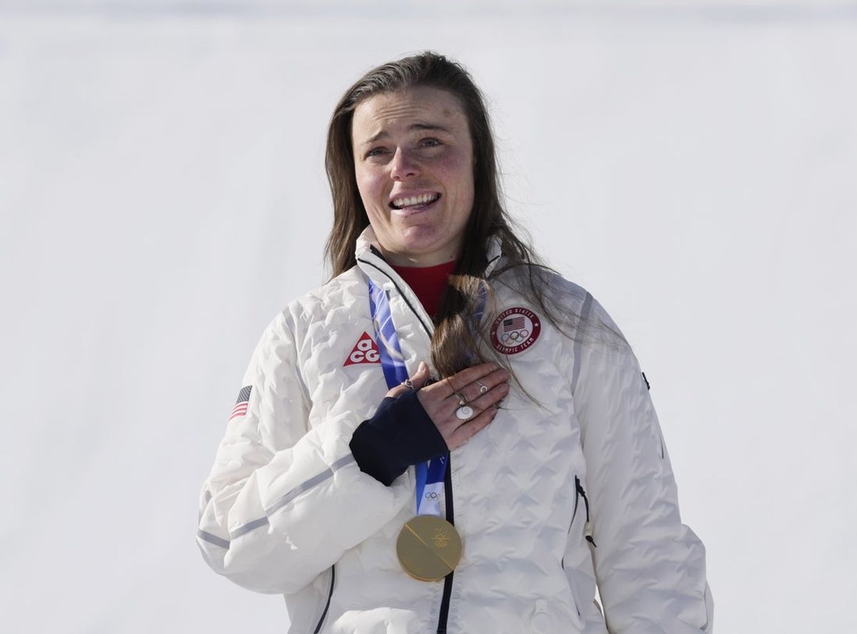 Feb 8, 2026; Cortina d'Ampezzo, Italy; Breezy Johnson of the United States celebrates on the podium with her gold medal in the women's downhill alpine skiing race during the Milano Cortina 2026 Olympic Winter Games at Tofane Alpine Skiing Centre. Mandatory Credit: Michael Madrid-Imagn Images