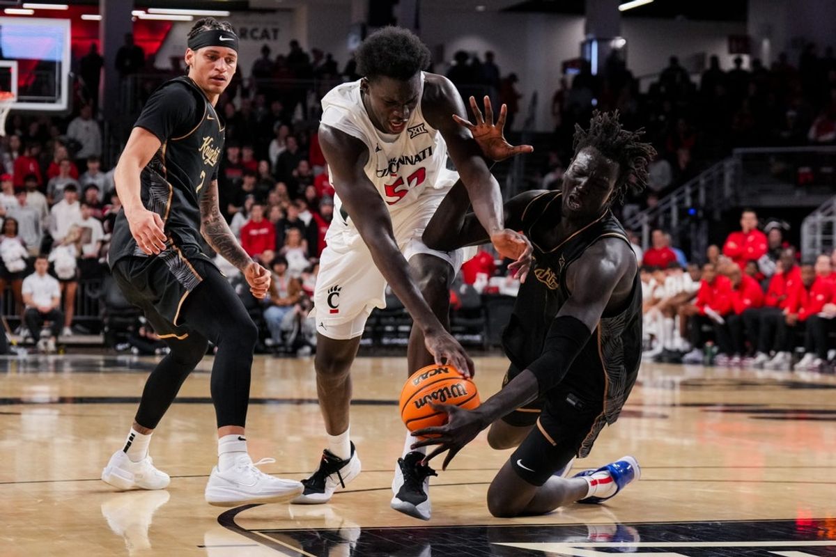 Feb 8, 2026; Cincinnati, Ohio, USA;  Cincinnati Bearcats center Moustapha Thiam (52) battles for the loose ball against UCF Knights center John Bol (7) in the first half at Fifth Third Arena. Mandatory Credit: Aaron Doster-Imagn Images