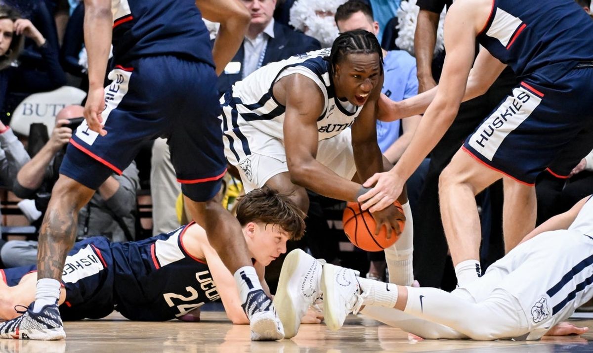 Feb 11, 2026; Indianapolis, Indiana, USA; Butler Bulldogs forward Efeosa Oliogu-Elabor (4) recovers a loose ball in front of UConn Huskies guard Braylon Mullins (24) during the first half at Hinkle Fieldhouse. Mandatory Credit: Robert Goddin-Imagn Images