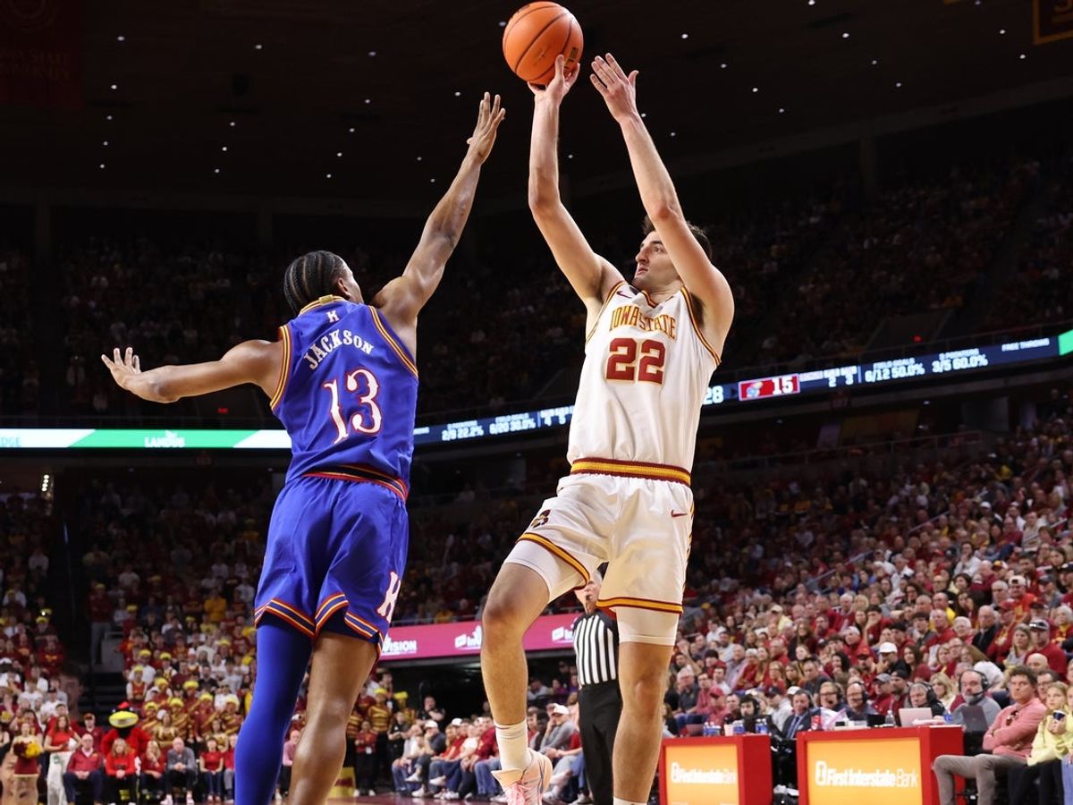 Feb 14, 2026; Ames, Iowa, USA; Iowa State Cyclones forward Milan Momcilovic (22) shoots over the hands of Kansas Jayhawks guard Elmarko Jackson (13) during the first half at James H. Hilton Coliseum. Mandatory Credit: Reese Strickland-Imagn Images