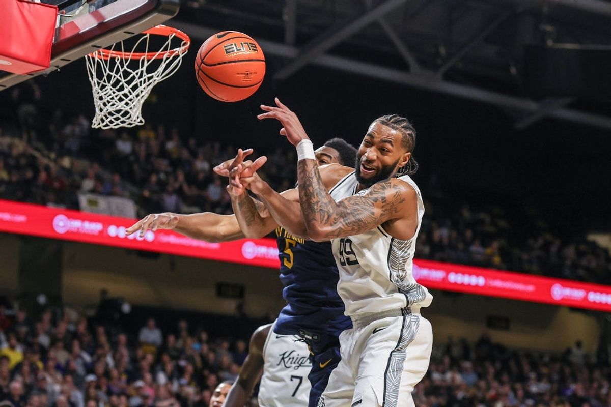 Feb 14, 2026; Orlando, Florida, USA; UCF Knights forward Jordan Burks (99) and West Virginia Mountaineers forward DJ Thomas (5) jump for the rebound during the first half at Addition Financial Arena. Mandatory Credit: Mike Watters-Imagn Images