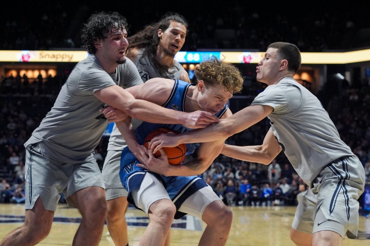 Feb 17, 2026; Cincinnati, Ohio, USA;  Villanova Wildcats forward Matt Hodge, middle, controls the ball after a rebound against Xavier Musketeers forward Jovan Milicevic, left, forward Tre Carroll, back, and guard All Wright, right, in the overtime period at the Cintas Center. Mandatory Credit: Aaron Doster-Imagn Images