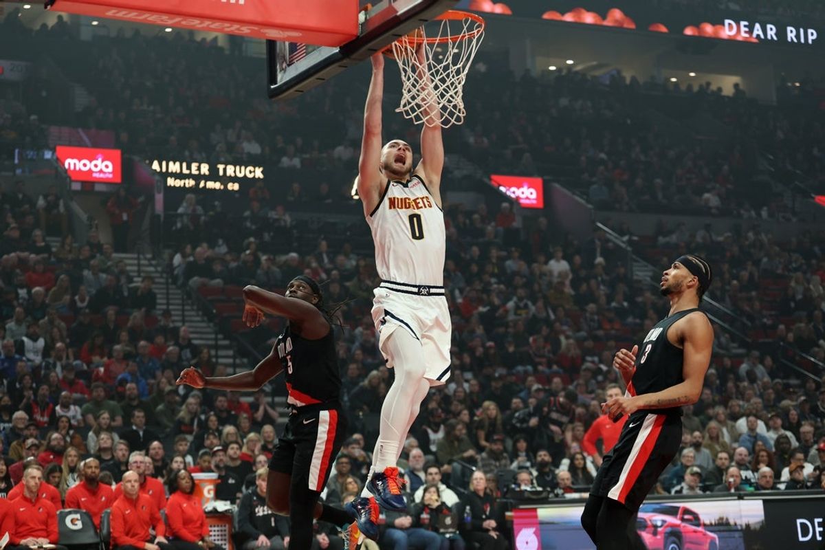 Feb 20, 2026; Portland, Oregon, USA;  Denver Nuggets guard Christian Braun (0) dunks over Portland Trail Blazers guard Jrue Holiday (5) and forward Toumani Camara (33) during first half at Moda Center. Mandatory Credit: Jaime Valdez-Imagn Images