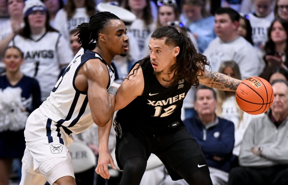 Feb 21, 2026; Indianapolis, Indiana, USA; Xavier Musketeers forward Tre Carroll (12) dribbles the ball against Butler Bulldogs forward Michael Ajayi (5) during the first half at Hinkle Fieldhouse. Mandatory Credit: Robert Goddin-Imagn Images