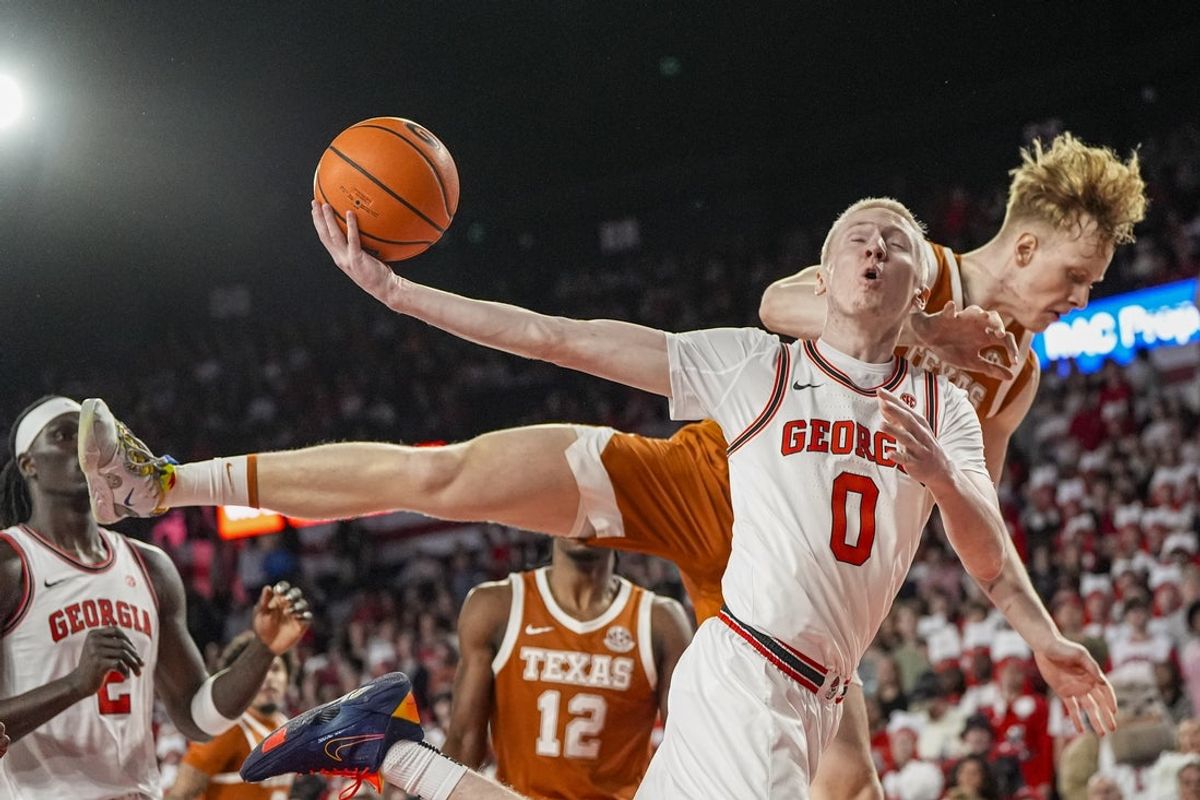 Feb 21, 2026; Athens, Georgia, USA; Georgia Bulldogs guard Blue Cain (0) is fouled from behind by Texas Longhorns center Matas Vokietaitis (8) during the first half at Stegeman Coliseum. Mandatory Credit: Dale Zanine-Imagn Images
