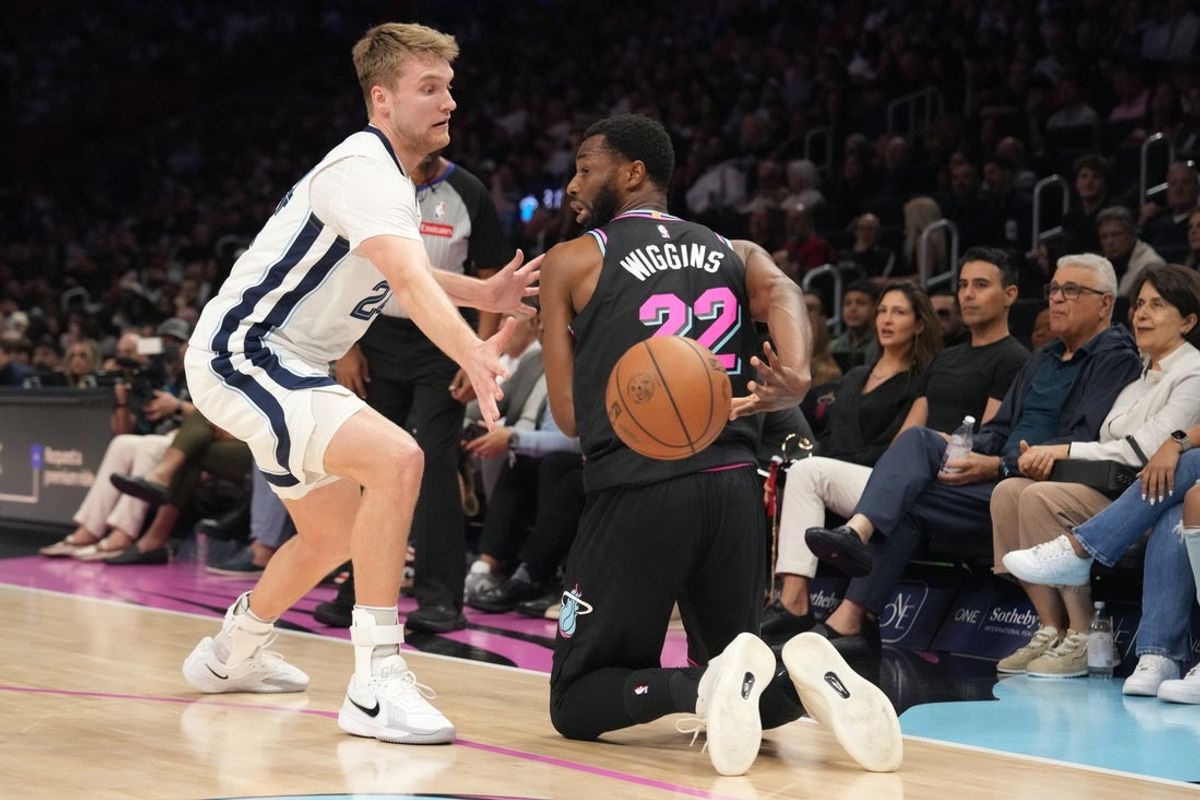 Feb 21, 2026; Miami, Florida, USA;  Miami Heat forward Andrew Wiggins (22) throws a pass behind his back as Memphis Grizzlies guard Cam Spencer (24) defends during the first half at Kaseya Center. Mandatory Credit: Jim Rassol-Imagn Images