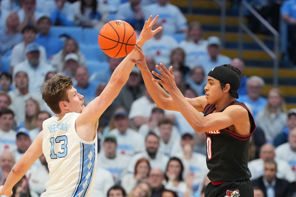 Feb 23, 2026; Chapel Hill, North Carolina, USA; Louisville Cardinals guard Mikel Brown Jr. (0) passes the ball as North Carolina Tar Heels center Henri Veesaar (13) defends in the second half at Dean E. Smith Center. Mandatory Credit: Bob Donnan-Imagn Images