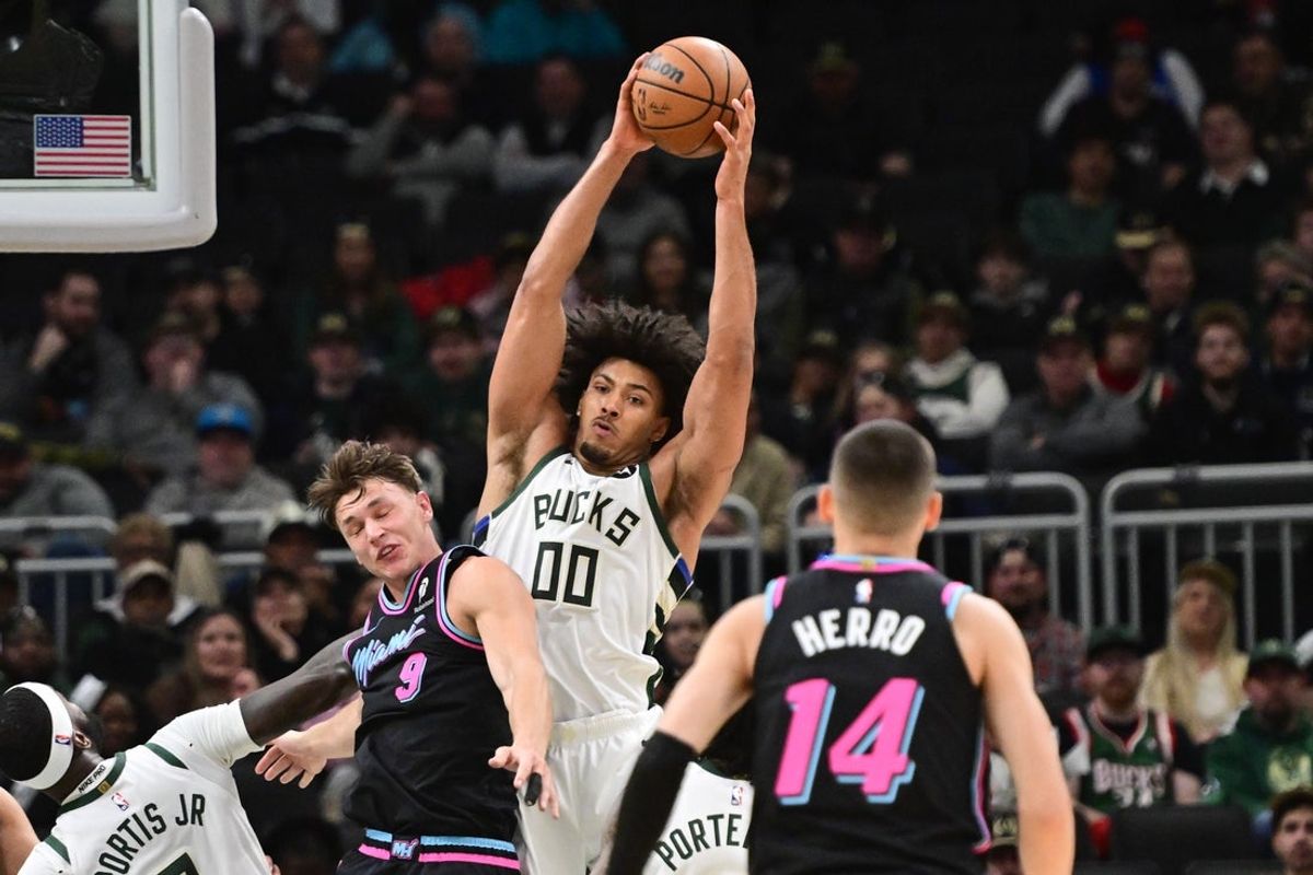 Feb 24, 2026; Milwaukee, Wisconsin, USA; Milwaukee Bucks center Jericho Sims (00) grabs a rebound against Miami Heat forward Pelle Larsson (9) in the first quarter at Fiserv Forum. Mandatory Credit: Benny Sieu-Imagn Images