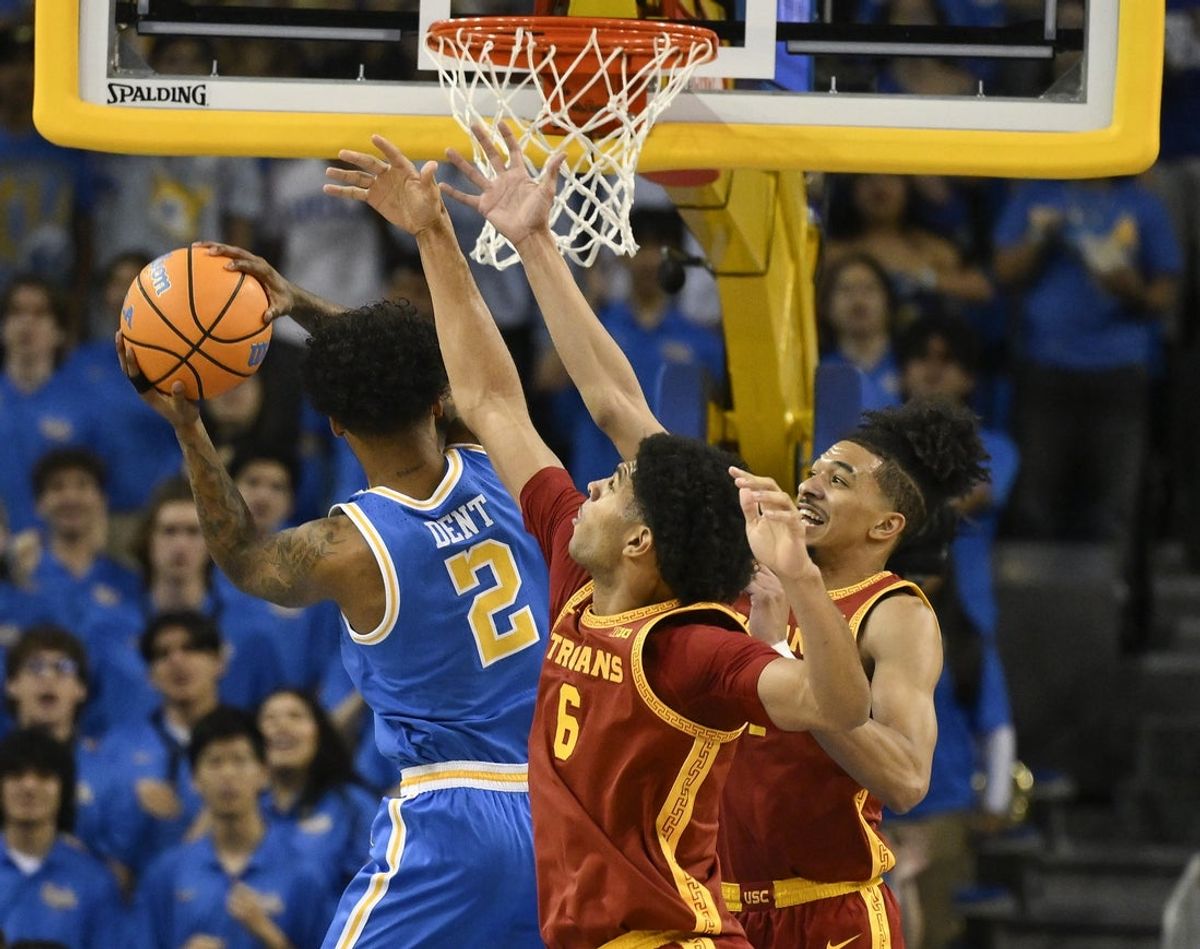 Feb 24, 2026; Los Angeles, California, USA; UCLA Bruins guard Donovan Dent (2) drives to the basket while guarded by Southern California Trojans forward Jacob Cofie (6) and guard Chad Baker-Mazara (4) during the first half at Pauley Pavilion presented by Wescom Financial. Mandatory Credit: Robert Hanashiro-Imagn Images