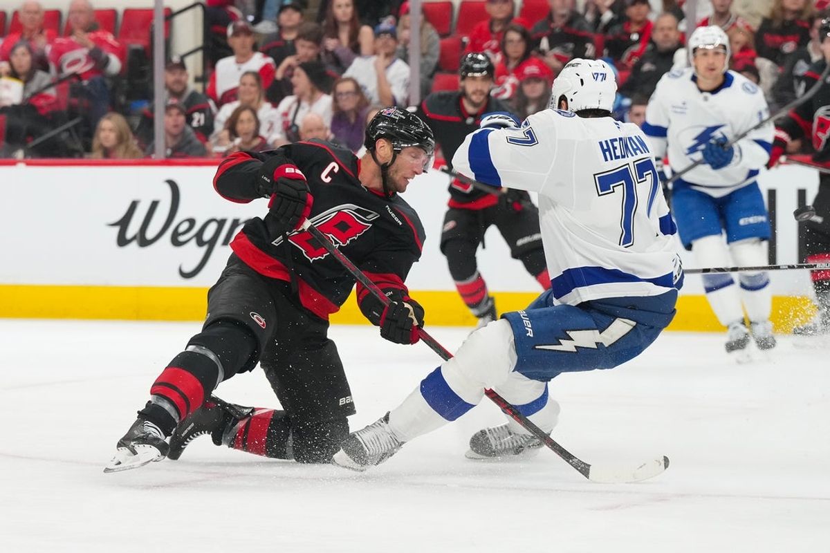 Feb 26, 2026; Raleigh, North Carolina, USA;  Carolina Hurricanes center Jordan Staal (11) shoots past Tampa Bay Lightning defenseman Victor Hedman (77) during the first period at Lenovo Center. Mandatory Credit: James Guillory-Imagn Images
