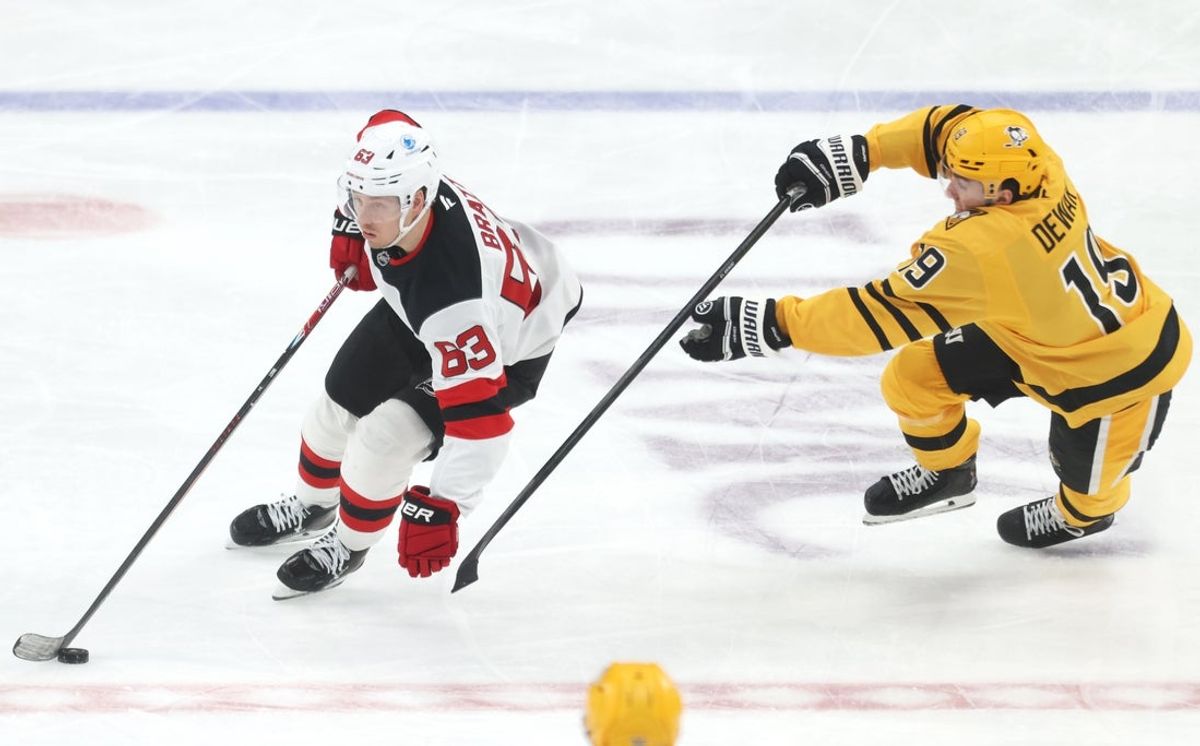 Feb 26, 2026; Pittsburgh, Pennsylvania, USA;  New Jersey Devils left wing Jesper Bratt (63) moves the puck against Pittsburgh Penguins center Connor Dewar (19) during the second period at PPG Paints Arena. Mandatory Credit: Charles LeClaire-Imagn Images