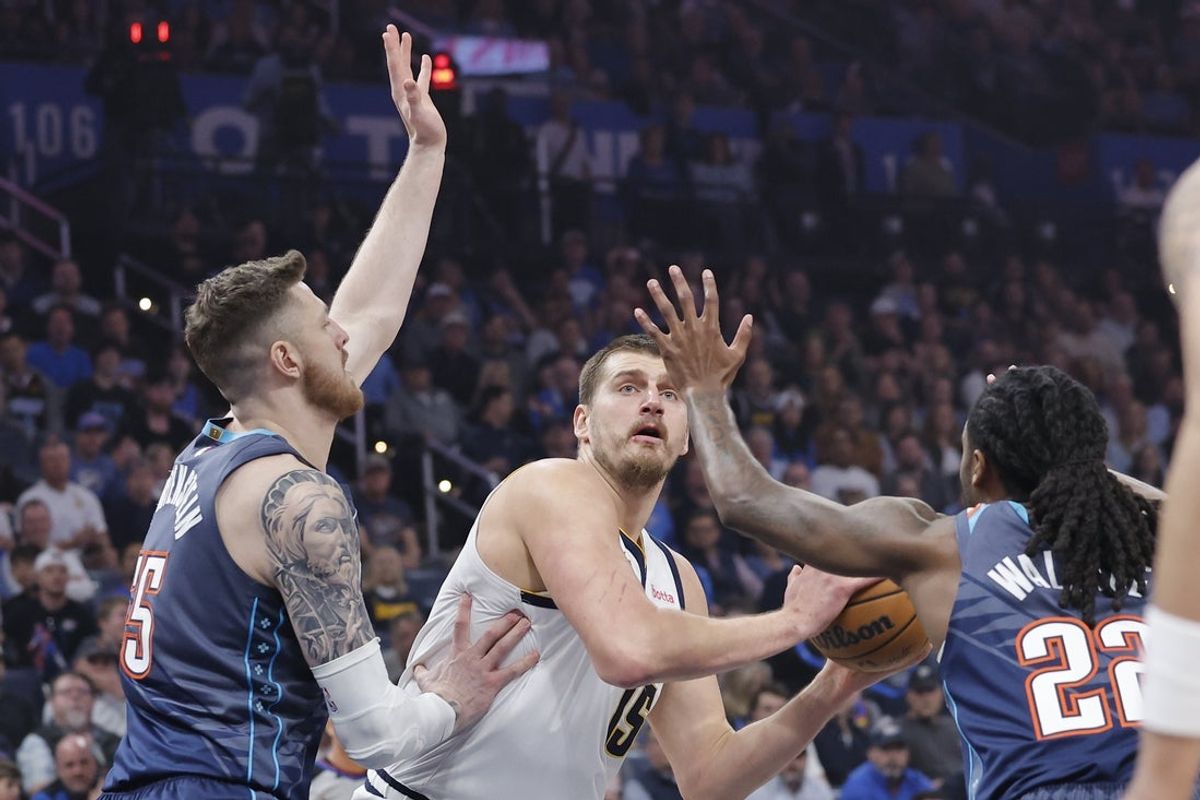 Feb 27, 2026; Oklahoma City, Oklahoma, USA; Denver Nuggets center Nikola Jokic (15) is defended by Oklahoma City Thunder center/forward Isaiah Hartenstein (55) and guard Cason Wallace (22) on a drive to the basket during the first quarter at Paycom Center. Mandatory Credit: Alonzo Adams-Imagn Images