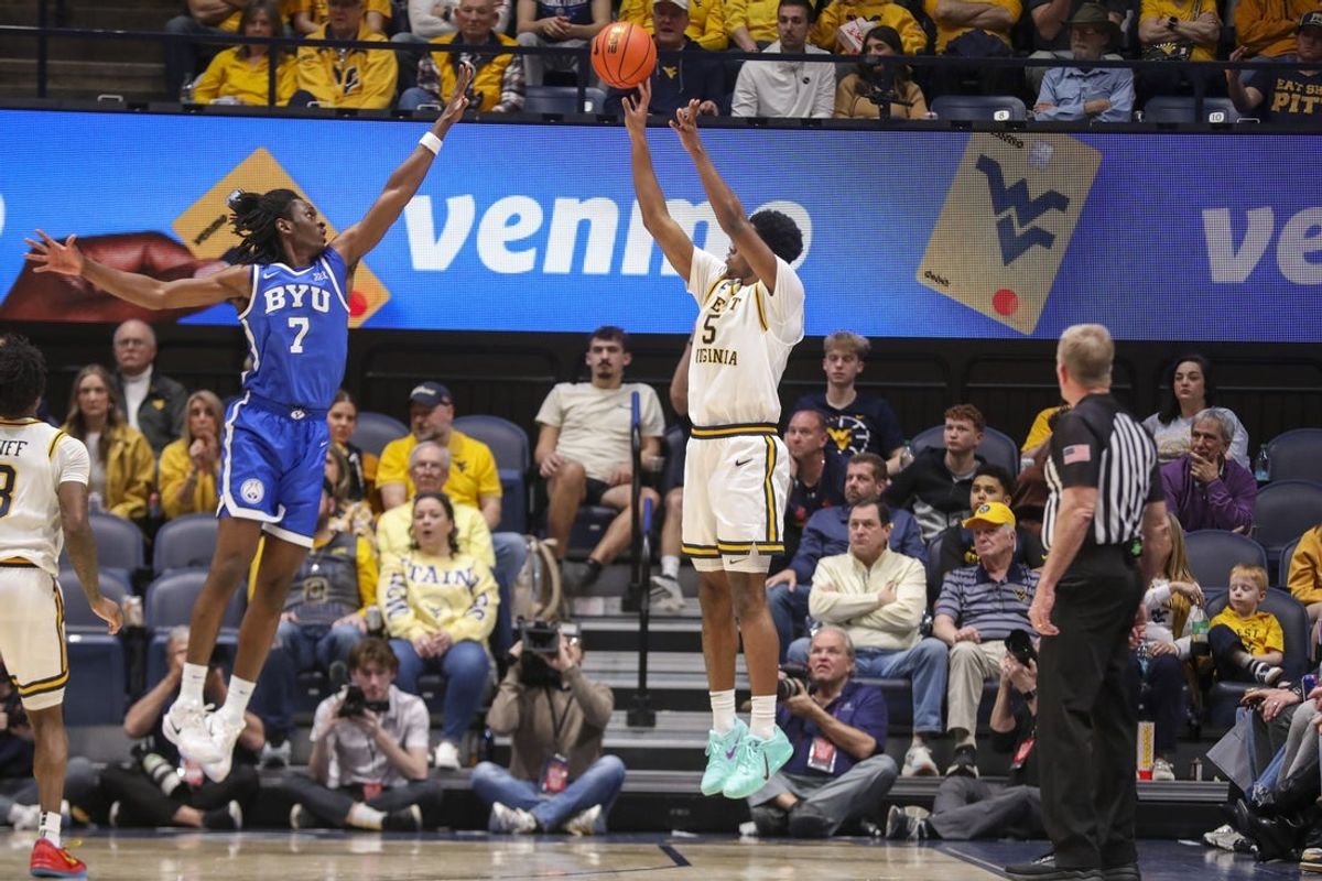 Feb 28, 2026; Morgantown, West Virginia, USA; West Virginia Mountaineers forward DJ Thomas (5) shoots a three point shot over BYU Cougars forward Khadim Mboup (7) during the first half at Hope Coliseum. Mandatory Credit: Ben Queen-Imagn Images