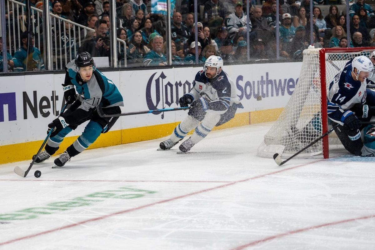 March 1, 2026; San Jose, California, USA; San Jose Sharks center Michael Misa (77) skates behind the net while being defended by Winnipeg Jets defenseman Dylan DeMelo (2) during the second period at SAP Center at San Jose. Mandatory Credit: Neville E. Guard-Imagn Images