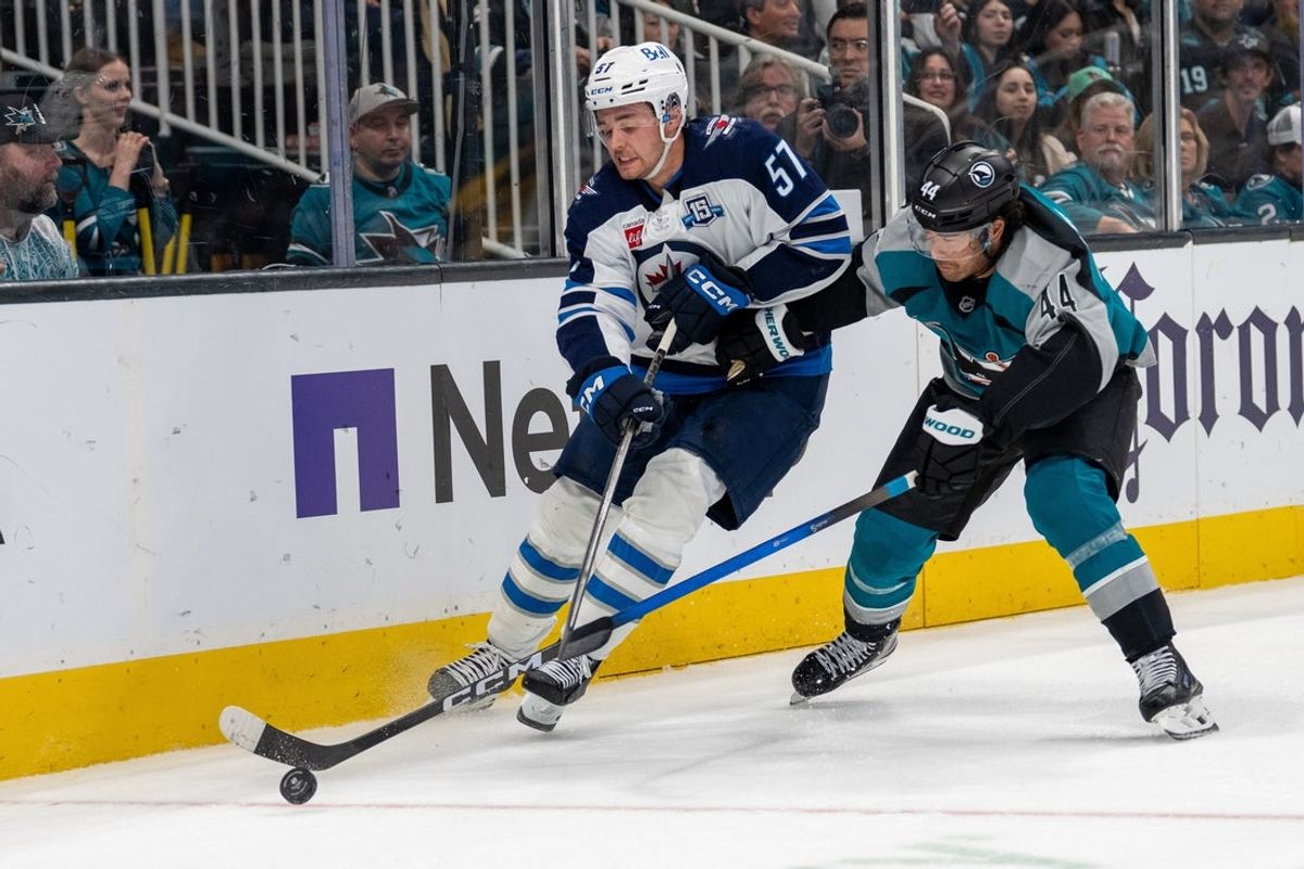 Feb 28, 2026; San Jose, California, USA; San Jose Sharks left wing Kiefer Sherwood (44) and Winnipeg Jets defenseman Elias Salomonsson (57) battle for the puck against the boards during the second period at SAP Center at San Jose. Mandatory Credit: Neville E. Guard-Imagn Images